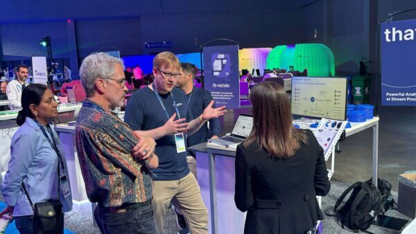 Ryan Wright explaining to multiple Current attendees how thatDot Streaming Graph event stream processor integrates with pipeline software like Kafka. At a small booth at Current, with Integration Options label on a diagram on the booth screen.